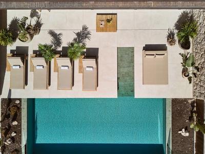 Widok z góry na basen z leżakami i roślinami na tarasie.