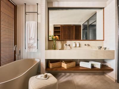 Nowoczesna łazienka z wolnostojącą wanną, dużym lustrem i drewnianymi półkami.