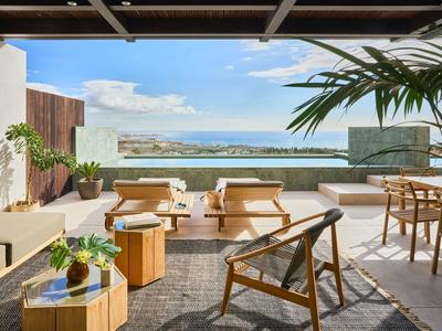 Jasny taras z nowoczesnymi meblami i widokiem na morze w słoneczną pogodę.