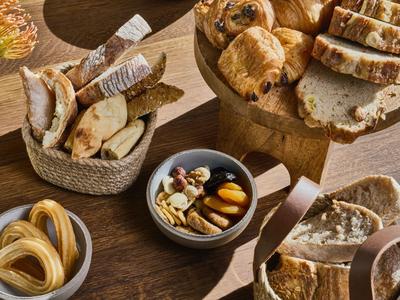 Różne rodzaje chleba i wypieków ułożone na drewnianym stole.