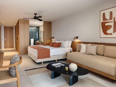 Nowoczesny pokój hotelowy z dużym łóżkiem, sofą i biurkiem.