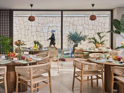 Elegantes Restaurant mit Holzmöbeln und Blick auf eine Steinmauer und einen Garten.