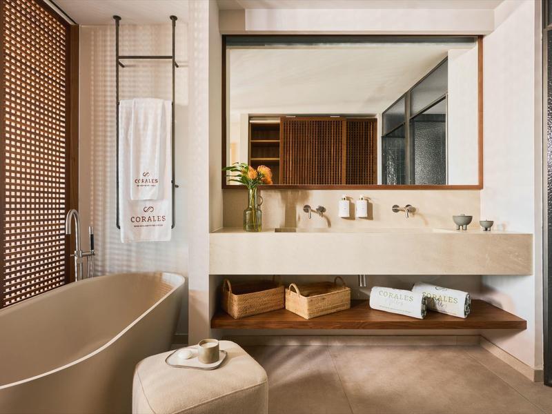 Nowoczesna łazienka z wolnostojącą wanną, dużym lustrem i drewnianymi półkami.