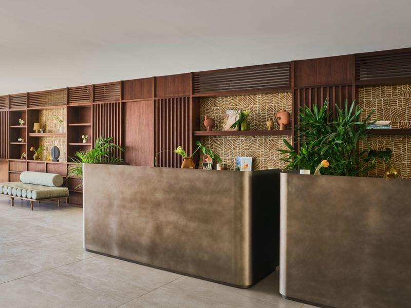 Nowoczesna recepcja hotelowa z dużymi roślinami i drewnianymi ścianami.