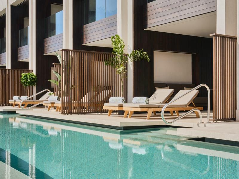 Nowoczesny taras hotelowy z leżakami i czystą wodą w basenie pod balkonami.