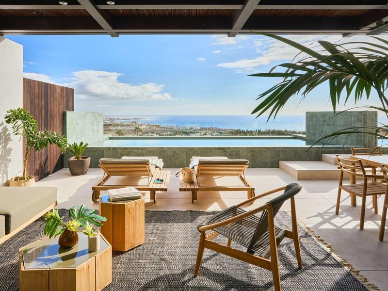 Jasny taras z nowoczesnymi meblami i widokiem na morze w słoneczną pogodę.