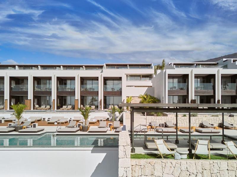 Nowoczesny kompleks hotelowy z basenem, parasolami i leżakami pod błękitnym niebem