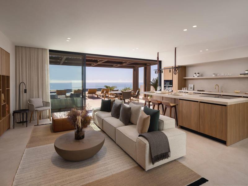 Nowoczesny salon z dużymi oknami otwierającymi się na taras z widokiem na morze.