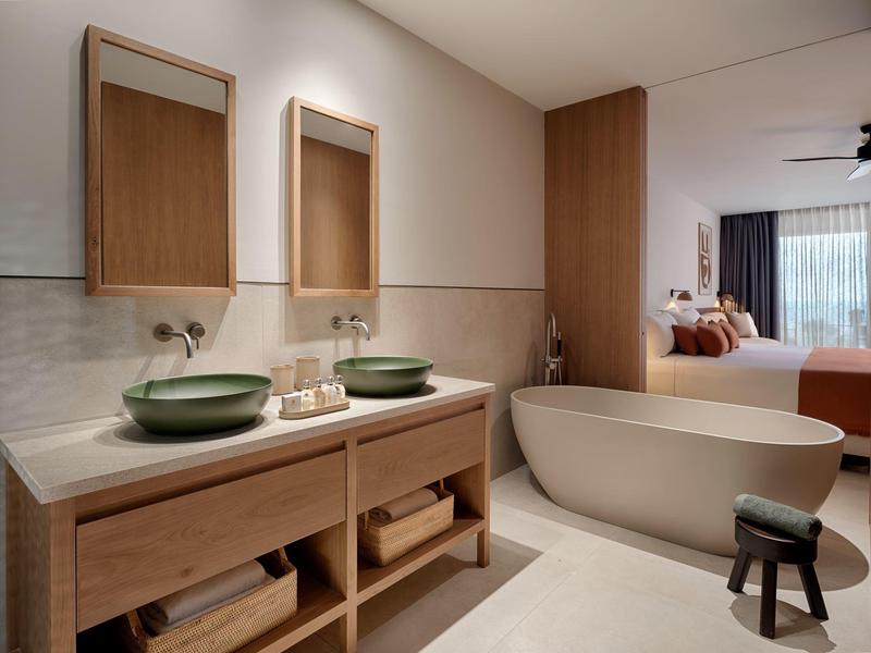 Nowoczesna łazienka z podwójną umywalką i wolnostojącą wanną w ciepłych drewnianych odcieniach.