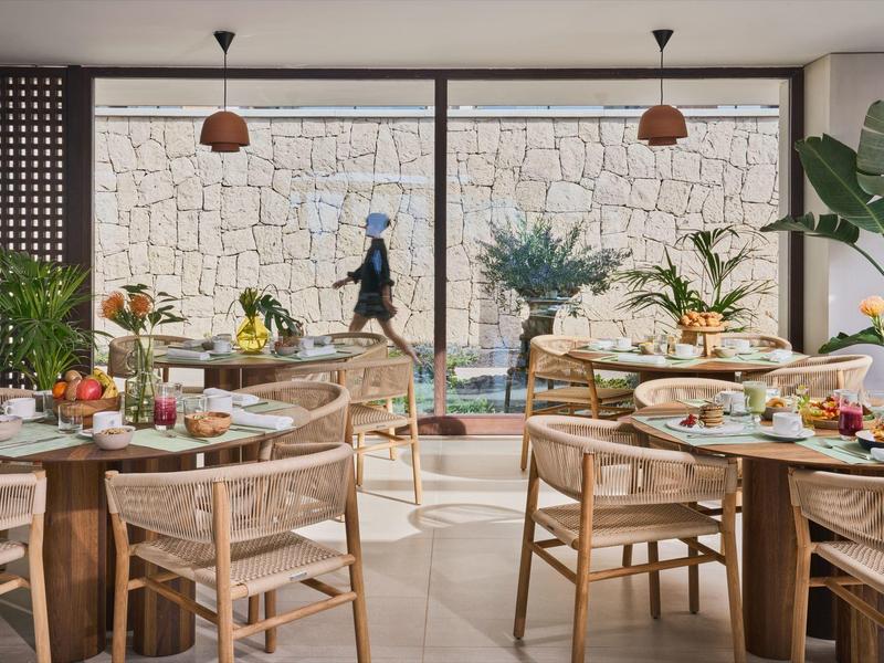 Elegancka restauracja z drewnianymi meblami z widokiem na kamienny mur i ogród.