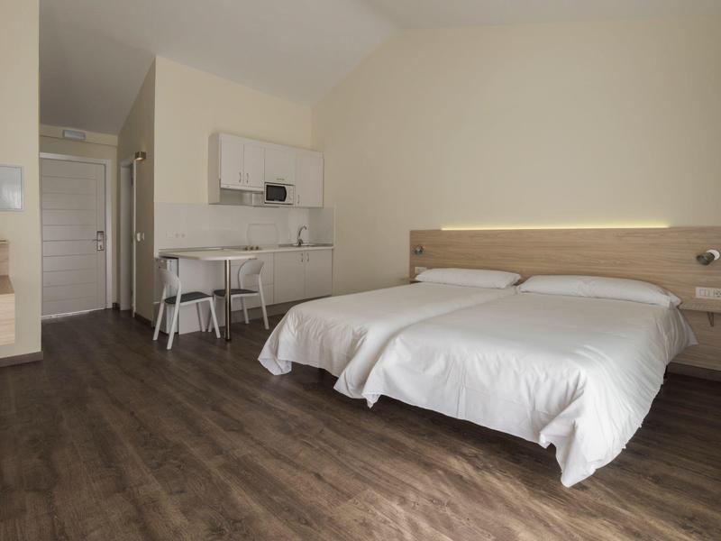 Camera d'hotel semplicemente arredata con letto matrimoniale, scrivania, sedia e pavimento in legno.