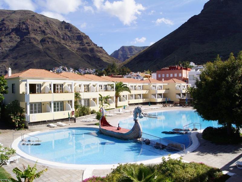 Hotel pool with gondola in front of mountain landscape and cloudy sky