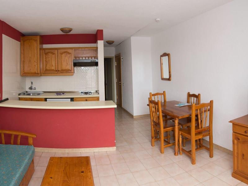 Kitchen and dining area with blue sofa, wooden furniture, and TV in a simple living space.