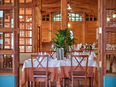 Interieur van een elegant restaurantgedeelte met houten wanden en gedekte tafels.