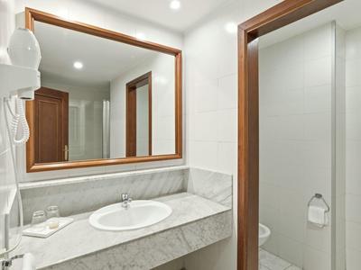 Heldere badkamer met witte wastafel, grote spiegel en aparte toiletruimte.