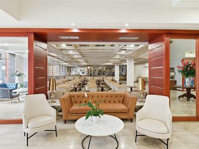 Elegante lounge met leren bank en stoelen voor een ruime open hotellobby.