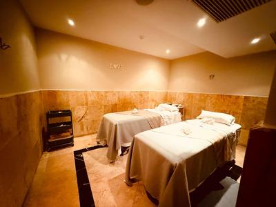 Treatment room with two massage tables, warmly lit and comfortably decorated.