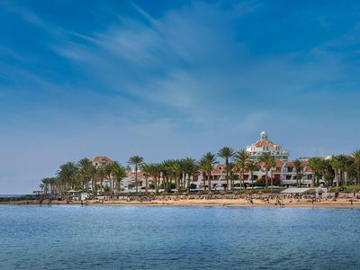 Complesso alberghiero con palme lungo la riva sotto un cielo azzurro sereno.