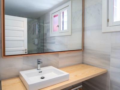 Piano lavabo in bagno d'hotel moderno con grande specchio, piano in legno e lavandino bianco.