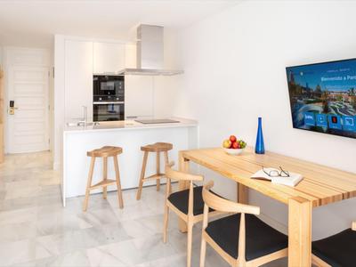 Area cucina e pranzo moderna con sedie in legno e sgabelli in colori chiari.