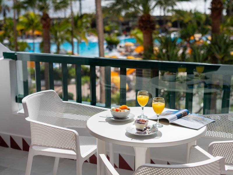 Terrazza dell'hotel con tavolo e sedie, colazione e vista sulla piscina.
