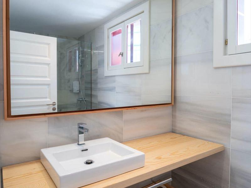 Piano lavabo in bagno d'hotel moderno con grande specchio, piano in legno e lavandino bianco.