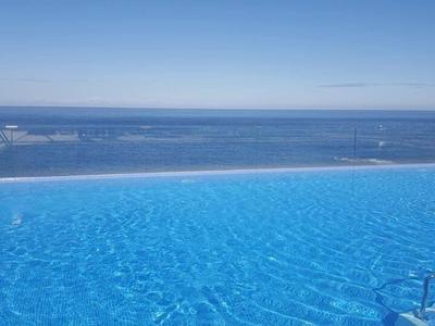 Infinity pool with clear water overlooking the sea under a blue sky.