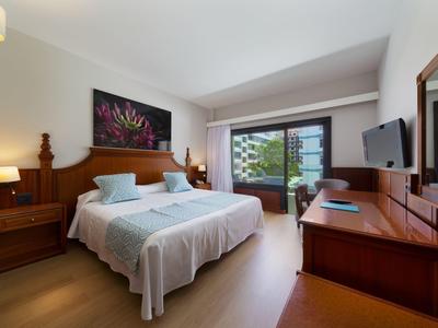 Modern hotel room with double bed, desk, TV, and balcony view.