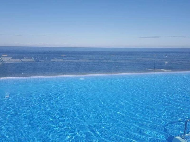 Infinity pool with clear water overlooking the sea under a blue sky.