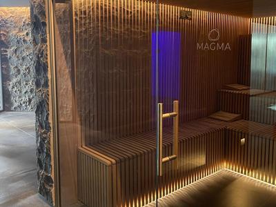 Moderner Saunabereich mit Holzverkleidung, blauer Beleuchtung und Marmorboden