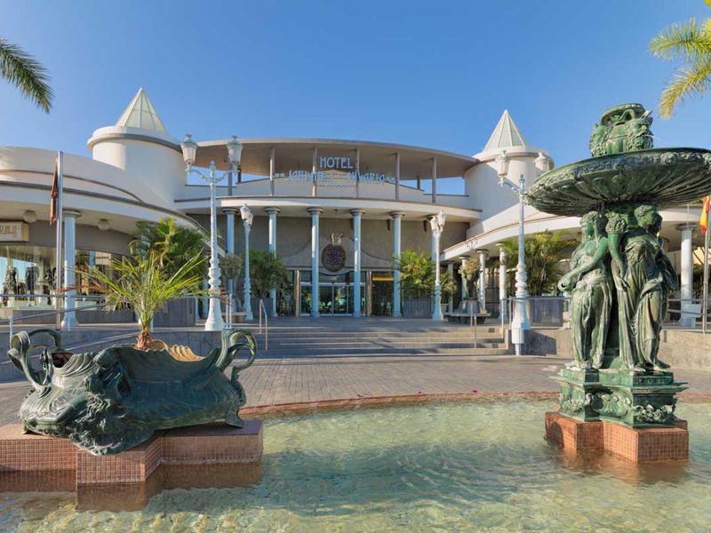 Großes Gebäude mit Säulen und runden Türmen, davor ein Brunnen mit Figuren und klarem Wasser.