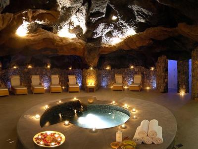Salle de spa confortable dans une grotte avec piscine ronde, bougies et équipements de bien-être.