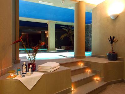 Espace spa tamisé avec escalier menant à une piscine éclairée en bleu la nuit.