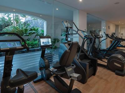 Moderne sportschool met loopbanden en hometrainers bij grote ramen en planten.