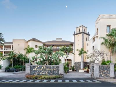 Hotelcomplex met palmbomen, zandstenen muur en heldere blauwe lucht bij daglicht