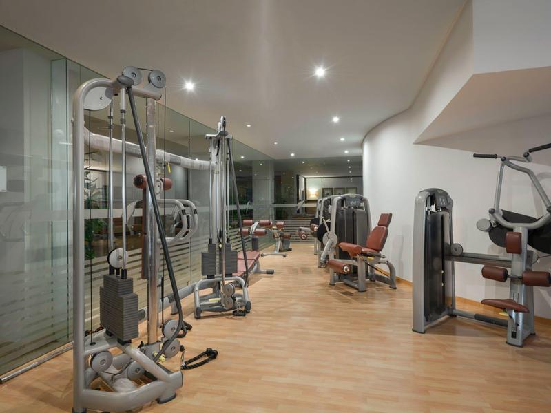 Salle de sport moderne d'hôtel avec divers appareils d'exercice et sol en bois.