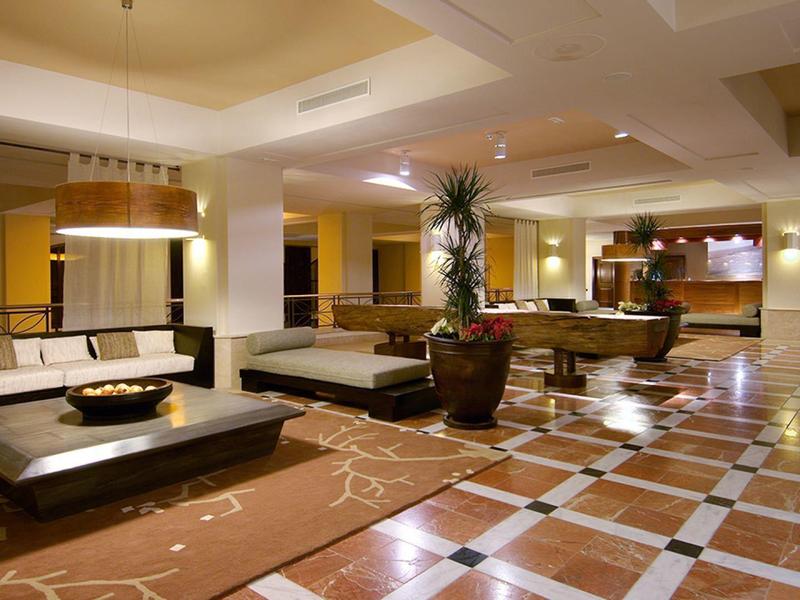 Grand hall d'hôtel avec sièges modernes, sols en marbre et éclairage chaleureux.