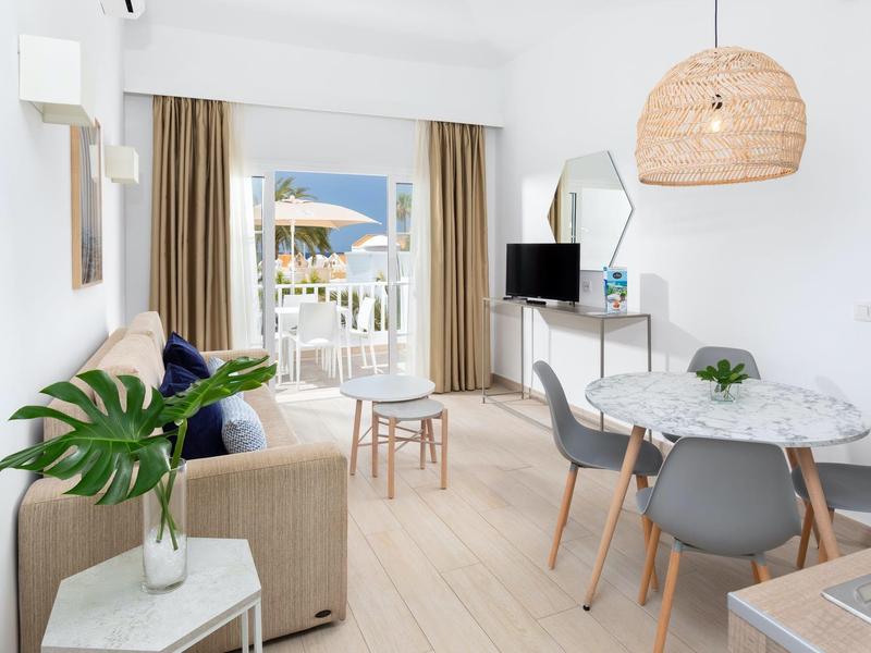 Soggiorno moderno con tavolo da pranzo, divano e balcone con vista mare.