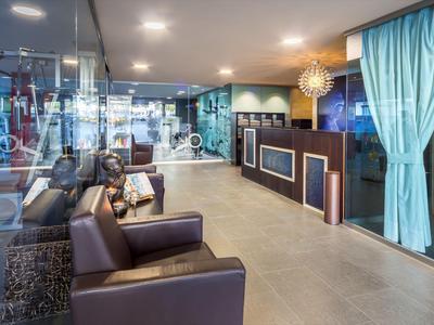 Moderní hotelová lobby s koženými pohovkami, recepcí a světlými závěsy.