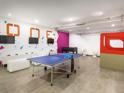 Nowoczesna sala rekreacyjna z stołem do ping ponga, sofą i kolorową dekoracją ścian.