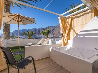 Luxusní venkovní sprcha s vířivkou, židlí, slunečníkem a výhledem na hory.