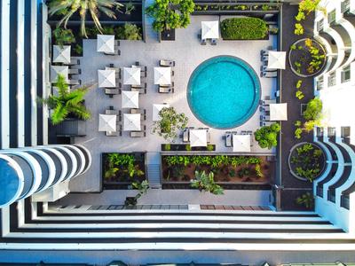 Vue aérienne d'un hôtel avec une piscine ronde, des transats et une architecture moderne.