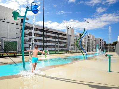 Kinderen spelen in een modern spraypark met waterspelen onder een heldere lucht.