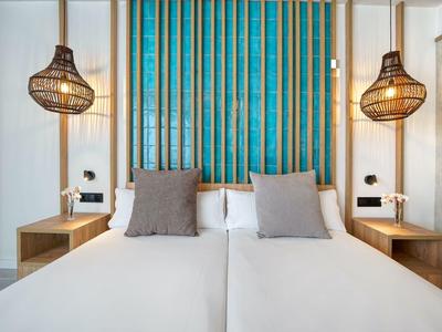 Modern hotelkamer met twee eenpersoonsbedden, stijlvolle lampen en blauwe wanddecoratie.