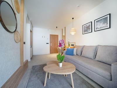 Lichte moderne woonkamer met grijze bank, houten salontafel en wanddecoraties.