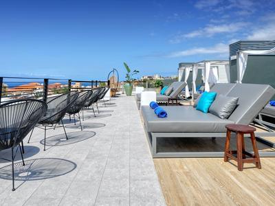 Dakterras met ligstoelen, zitplaatsen en zeezicht onder een heldere lucht.