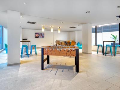 Moderne lounge met tafelvoetbal, blauwe barkrukken en panoramische ramen.