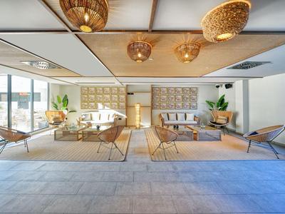 Lichte, moderne lounge met bamboemeubilair en grote ramen.