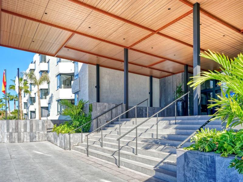 Hotelvoorkant met overdekte ingang, trap en vlaggen op de achtergrond.