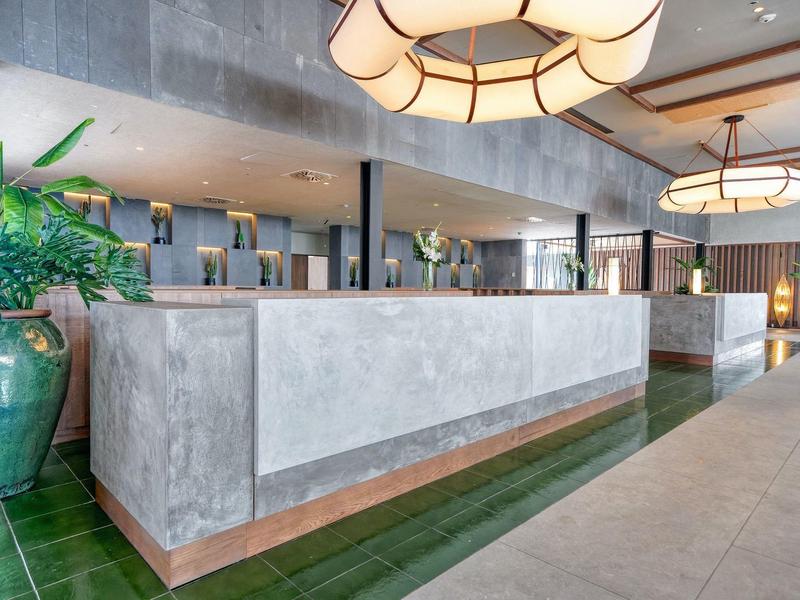 Modern hotelreceptie met betonnen balie en groene accenten